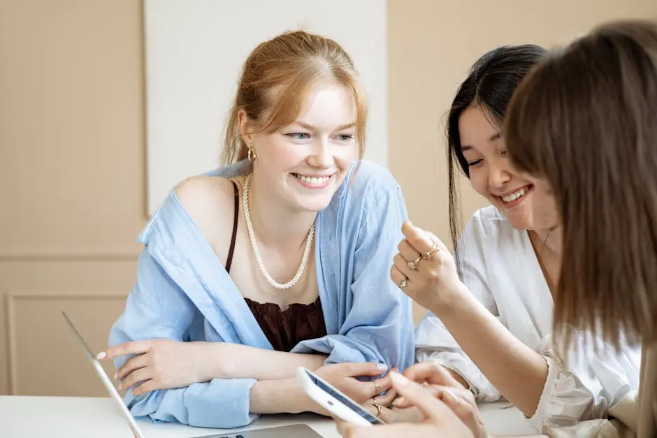 Three young women collaborating at a desk, sharing ideas and working together in a modern office environment.