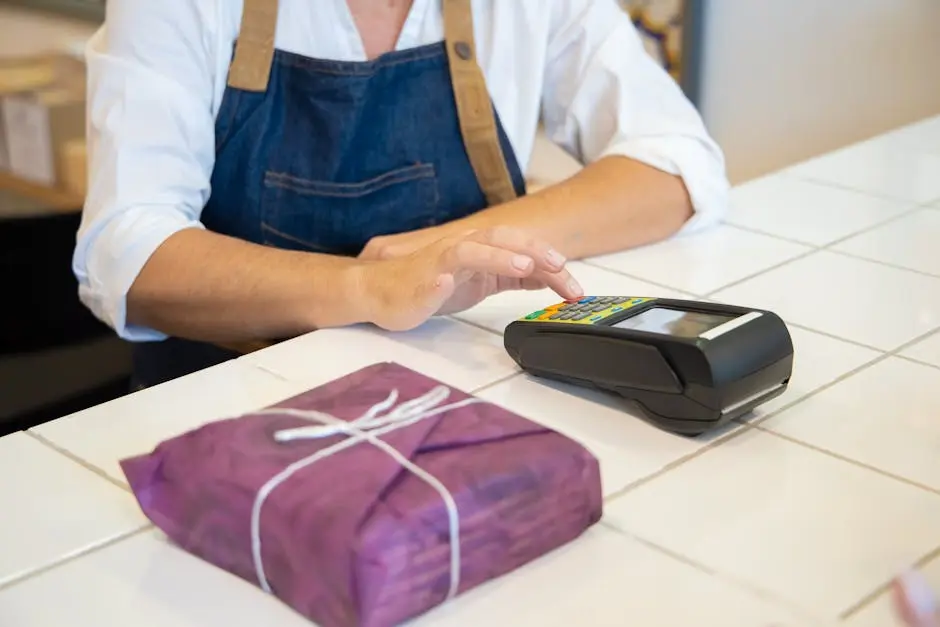A person using contactless payment at a retail counter in Portugal wearing an apron.