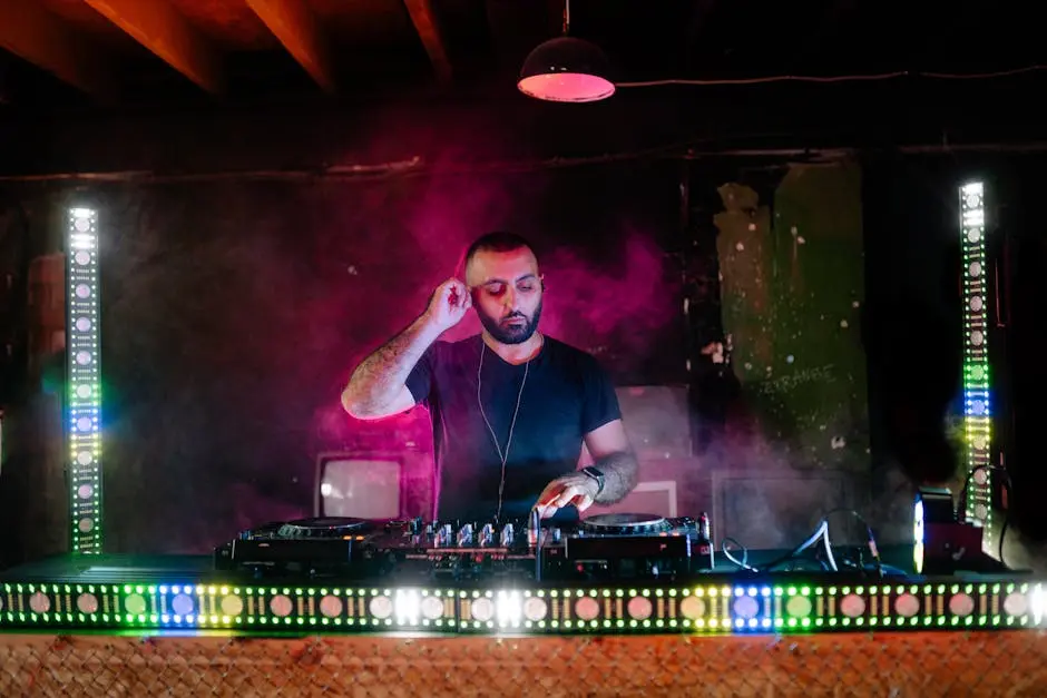 A DJ performs with vibrant light effects during a music event in a nightclub setting.