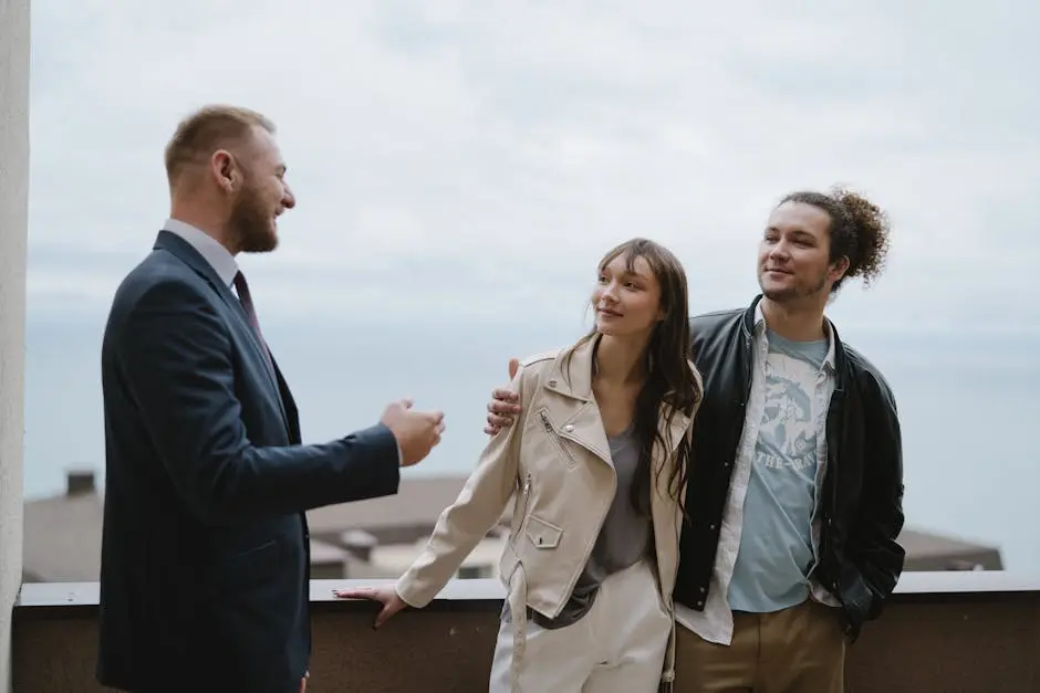 A young couple consults with a real estate agent on a balcony with scenic views.