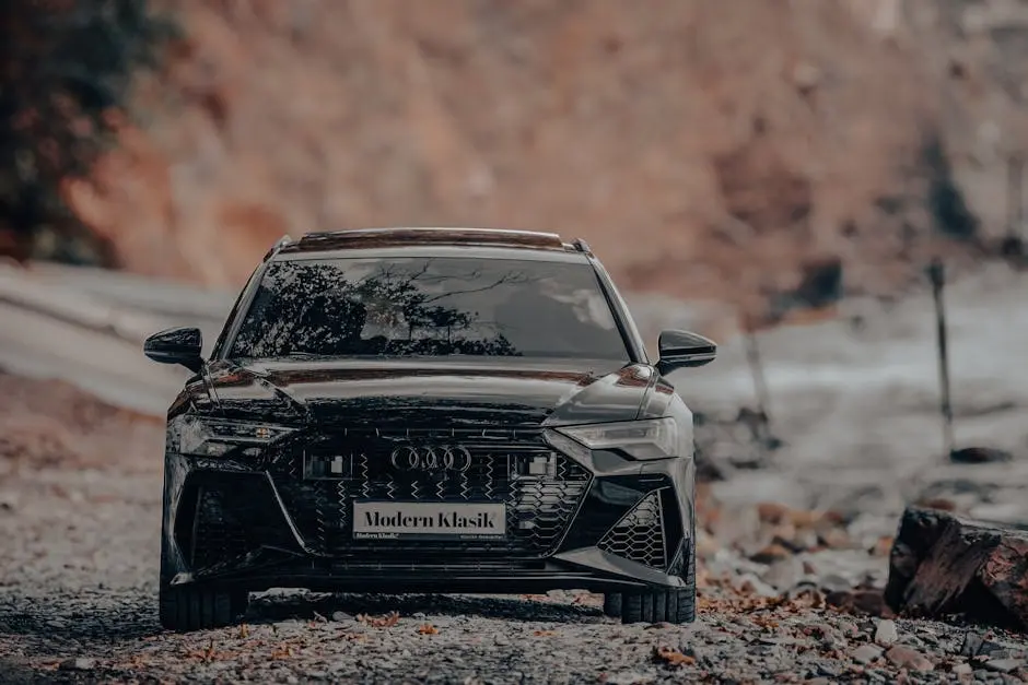 A sleek black luxury car parked outdoors on a gravel path with a blurred background.