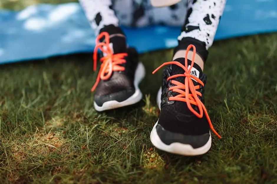 Close-up of sneakers with red laces on grassy field, ideal for sports and outdoor themes.