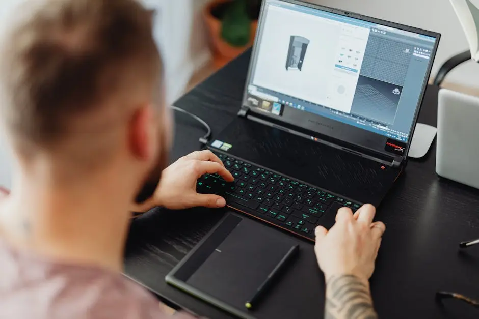Man using laptop and tablet for 3D design, showcasing modern digital work environment.
