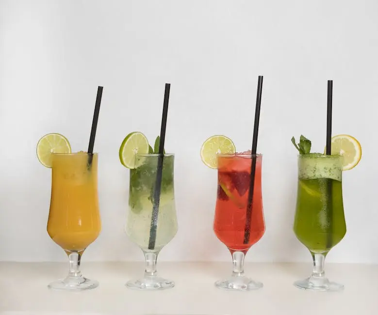 Four vibrant tropical beverages with limes and straws in glasses against a white background.