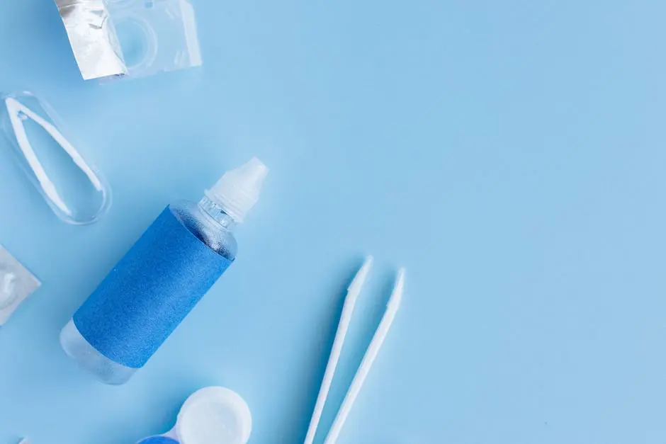 Flatlay of contact lens solution, case, and tweezers on blue background for eye care essentials.