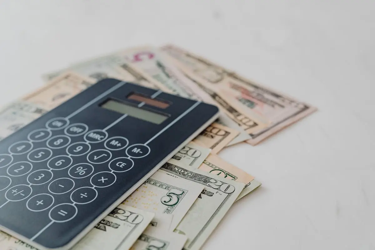 A close-up of a calculator and us dollar banknotes, symbolizing financial calculation and budgeting.