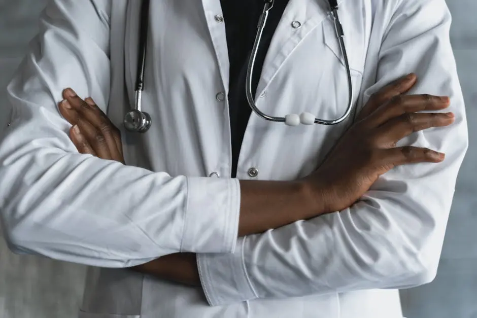 Close-up of a confident doctor in a lab coat standing with crossed arms and stethoscope.