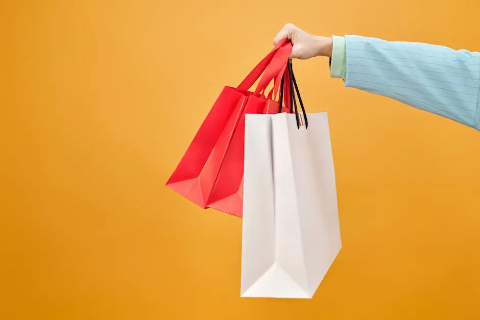 A hand holds colorful shopping bags against a bright yellow backdrop, highlighting retail shopping.