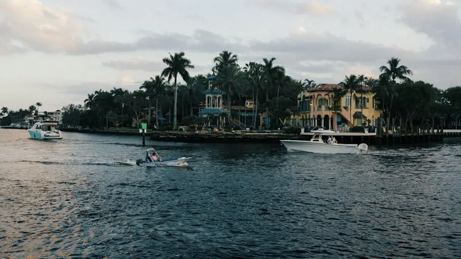 Tranquil boating scene on a tropical waterfront with luxurious homes.