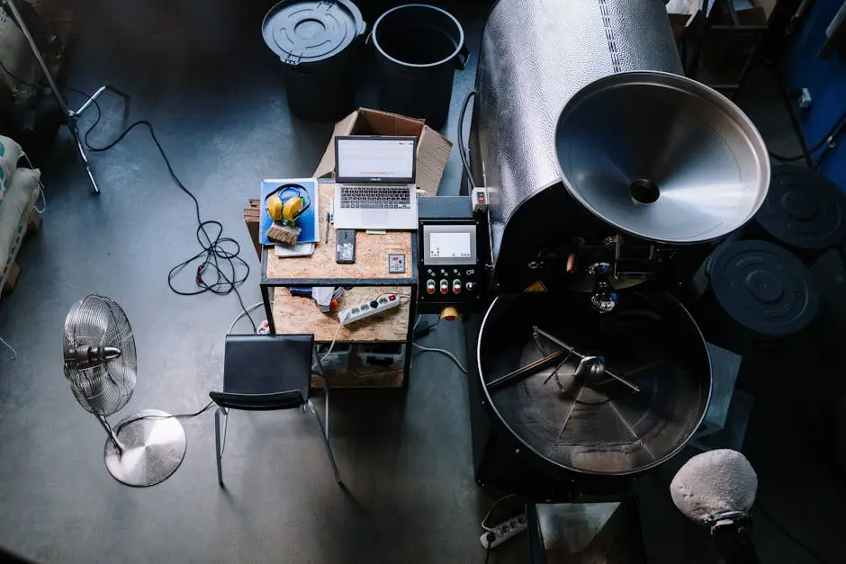 An overhead view of a coffee roastery workspace featuring equipment and a laptop.