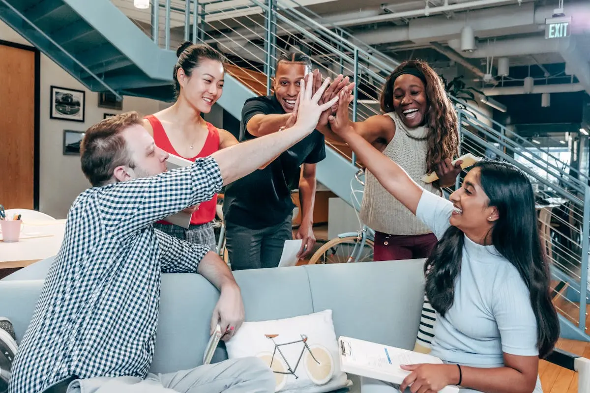 A multicultural office team high-fiving and celebrating a successful collaboration.