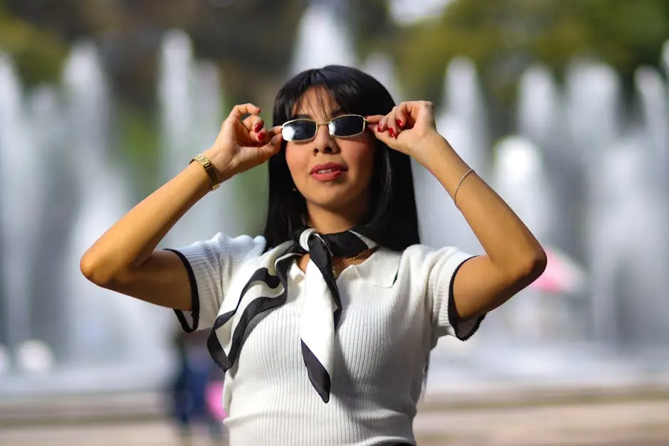 Woman posing stylishly in sunglasses with fountains in background, showcasing fashion.
