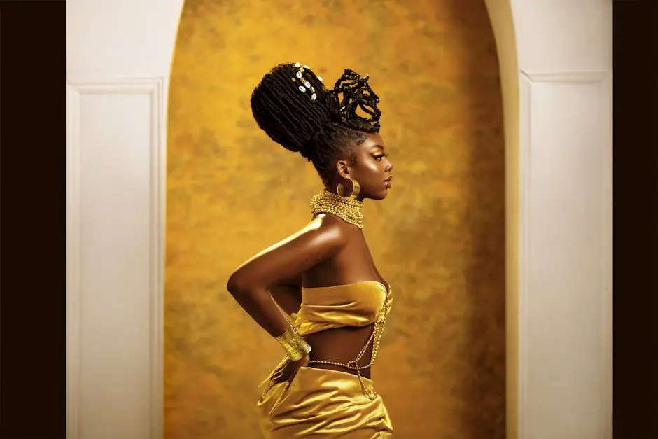 Profile of woman in elegant gold attire posing indoors against a golden backdrop.