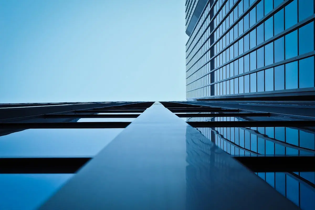 Low angle view of a modern skyscraper with reflective glass facade and blue sky.