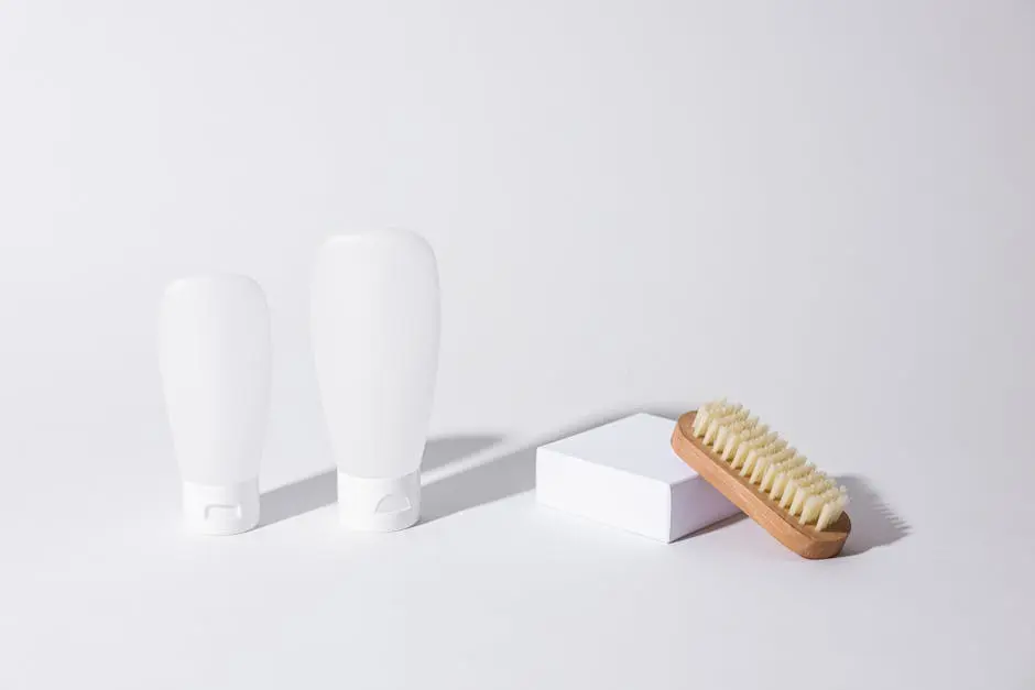 Clean minimalist photo of skincare bottles with a wooden brush on a white background.