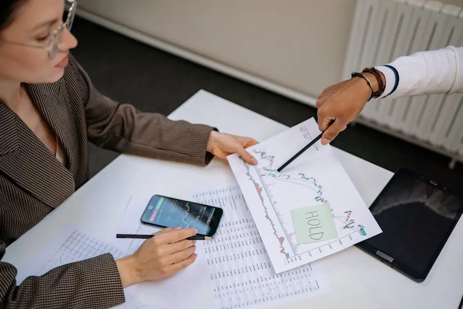 Two professionals analyzing stock market data and graphs at a desk.