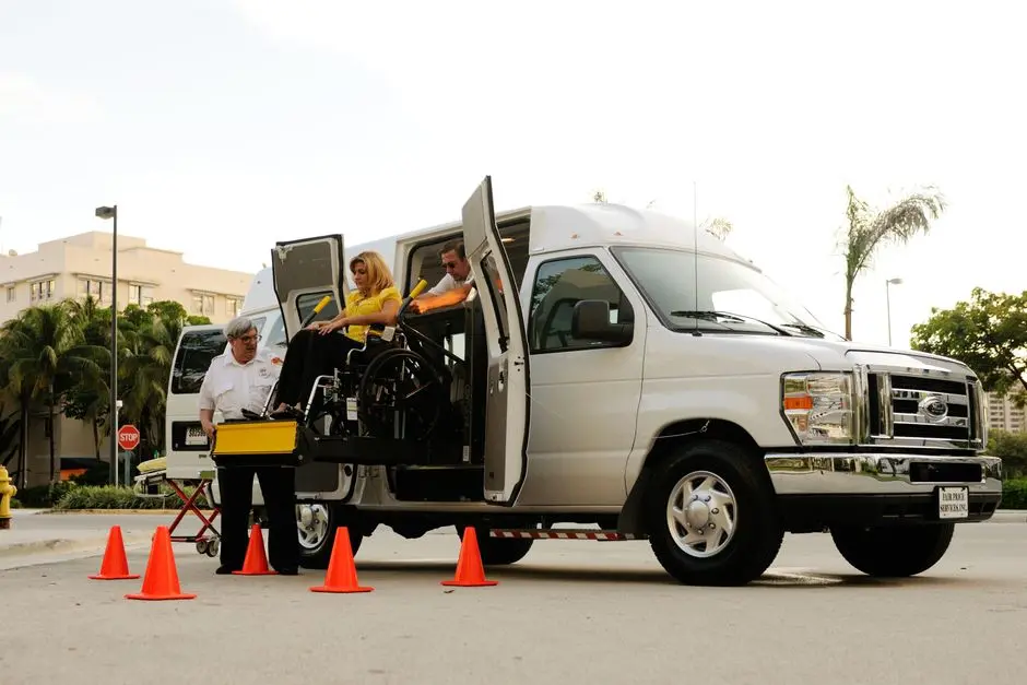 A wheelchair lift transfers a person into an accessible van on a sunny day.