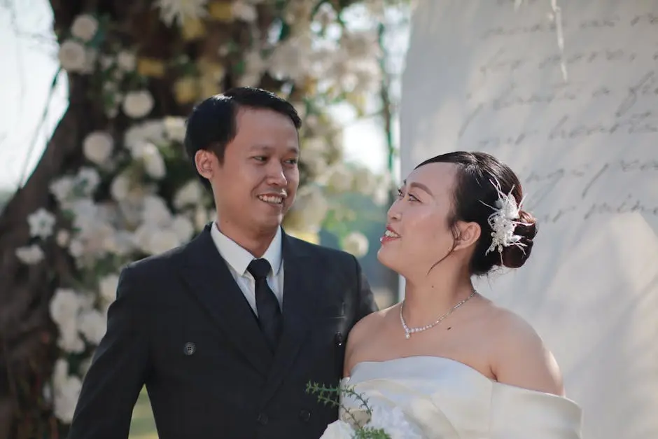 A joyful couple shares a moment at their outdoor wedding, surrounded by flowers.
