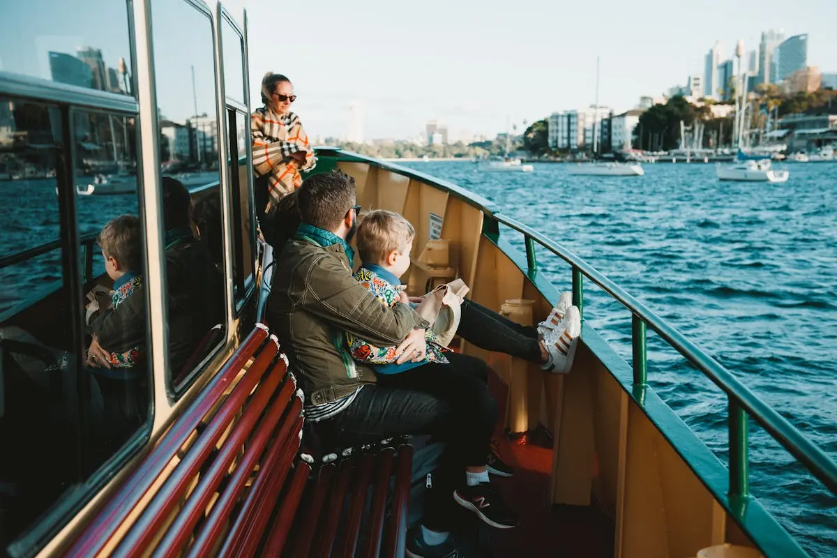 Father and child on a boat enjoying a sunny day on Sydney Harbor, with city skyline view.