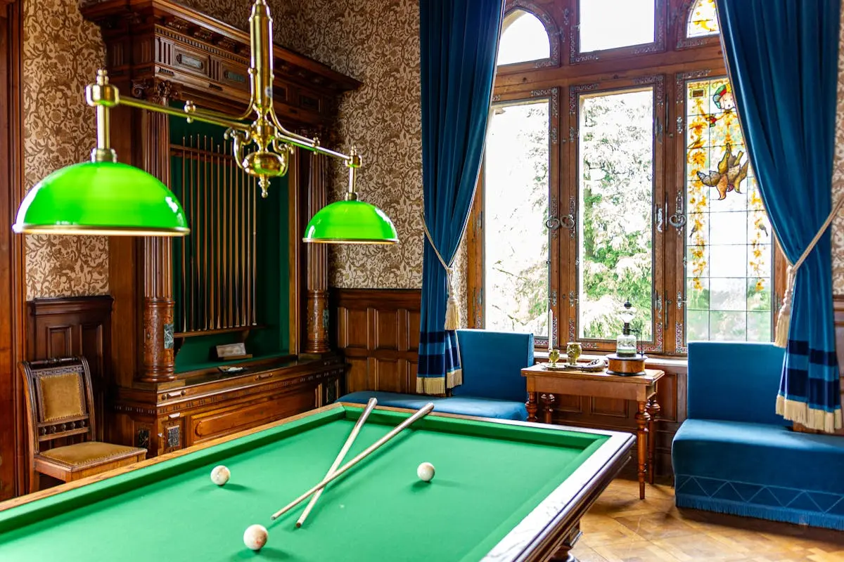 An elegant vintage billiard room with classic green felt table and stylish decor.
