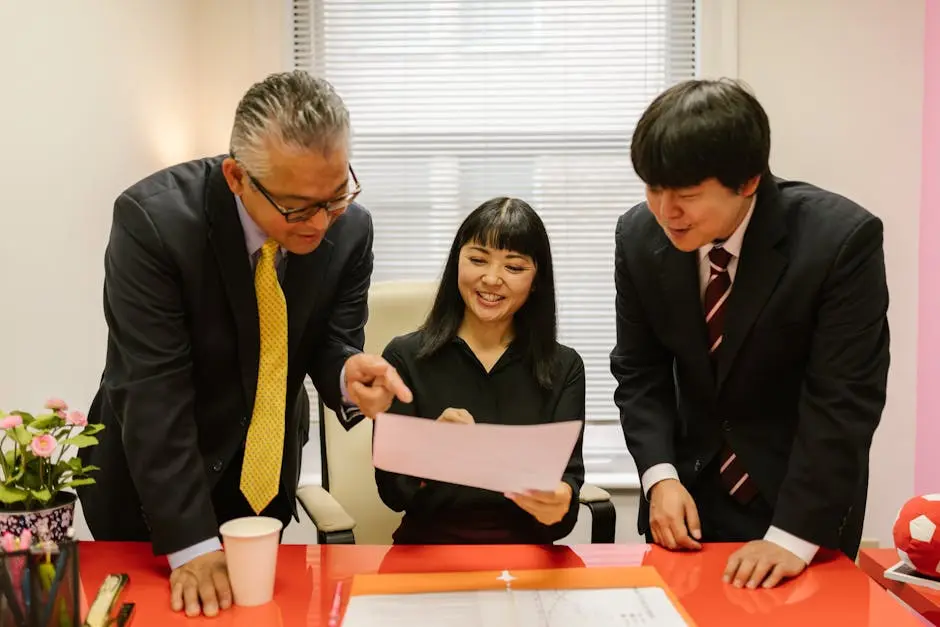 Three business professionals collaborating indoors with documents at a modern office desk.