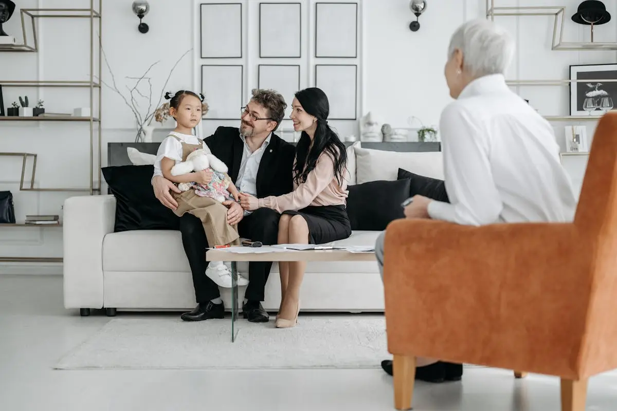 A family meets with a social worker in a cozy living room, discussing adoption details.