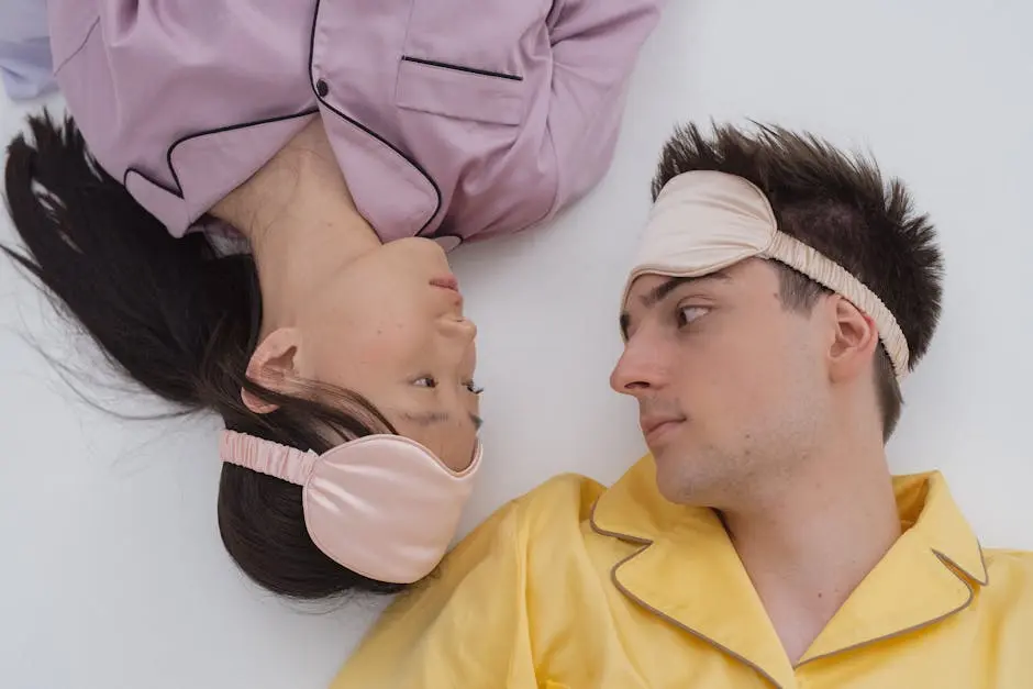 Asian woman and Caucasian man lying face to face in colorful pajamas and sleep masks.