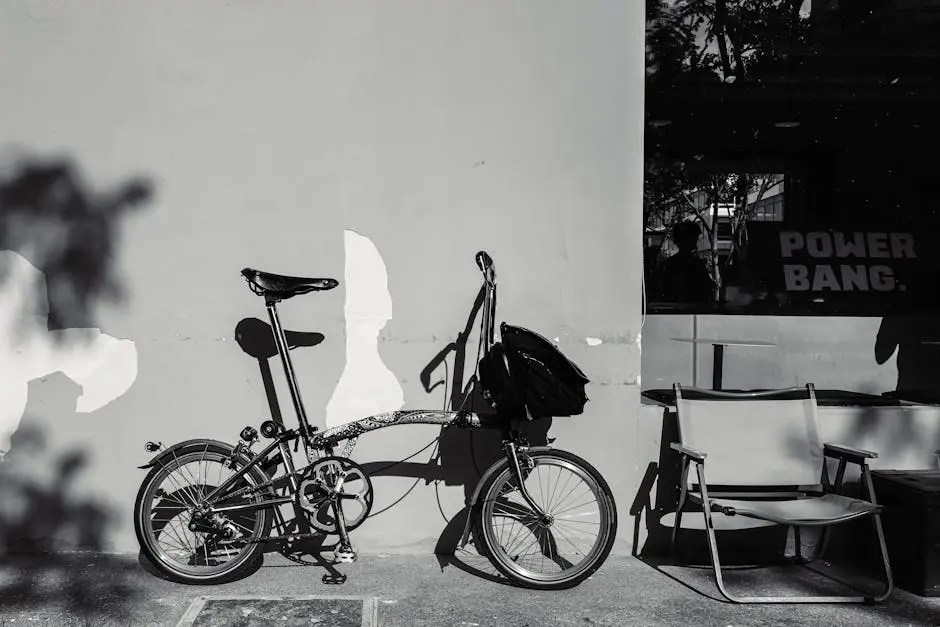 Stylish urban scene with a folding bicycle against a textured wall in black and white.