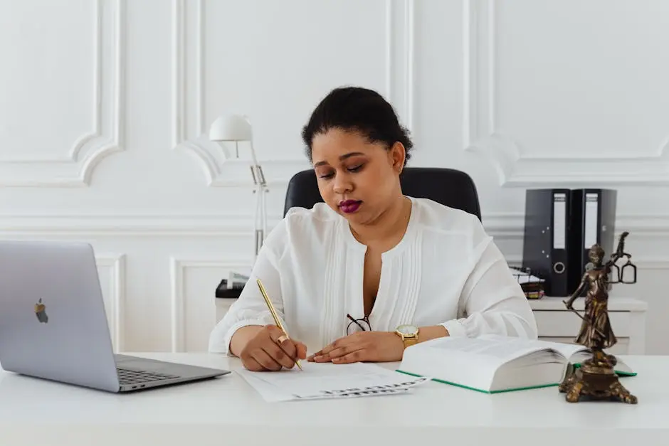 African American woman lawyer signing documents at a desk, symbolizing professionalism.
