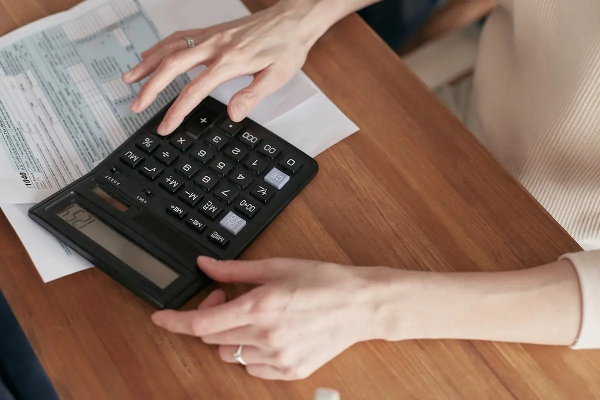 Close-up of a woman using a calculator and reviewing bills at home fractional cfo.
