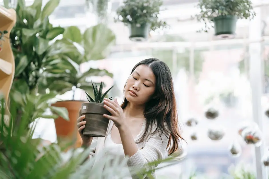 Asian woman carefully tending to a potted plant inside a store filled with greenery.