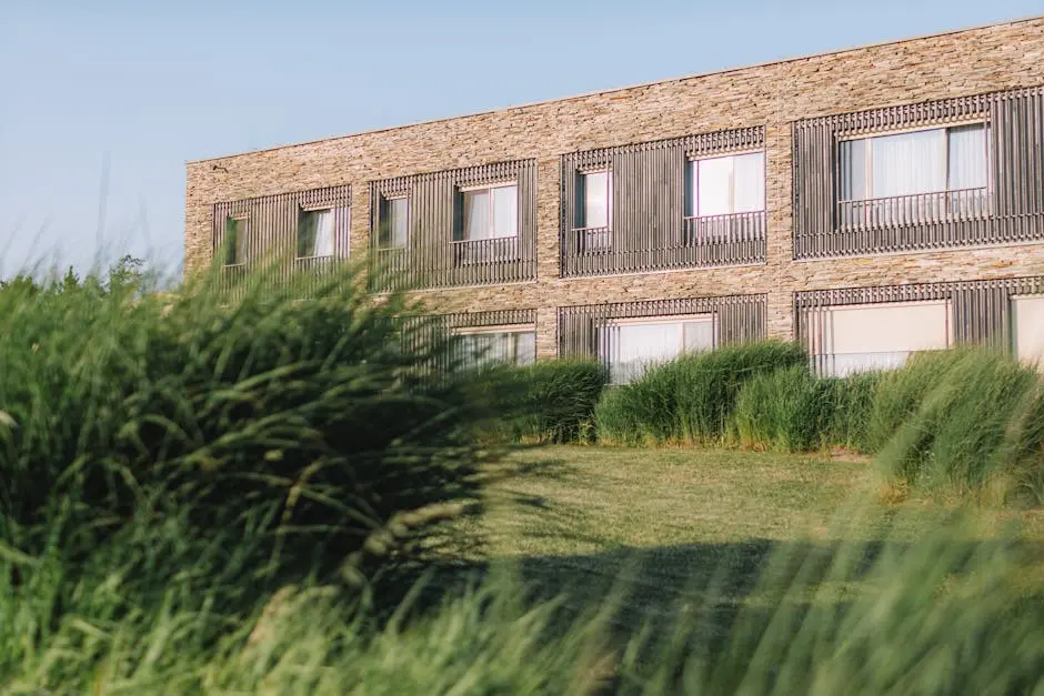 Contemporary stone building facade surrounded by lush green grass on a sunny day.