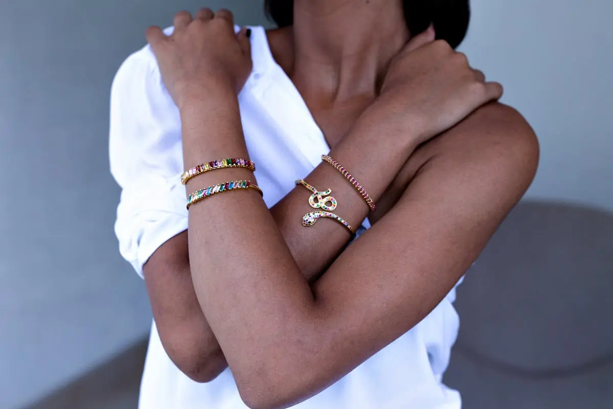 Close-up of a woman’s crossed arms adorned with colorful gemstone bracelets, showcasing elegance and style.