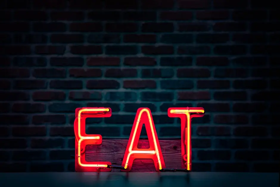 Vibrant neon &lsquo;EAT&rsquo; sign in red glowing boldly against a dark brick wall background.