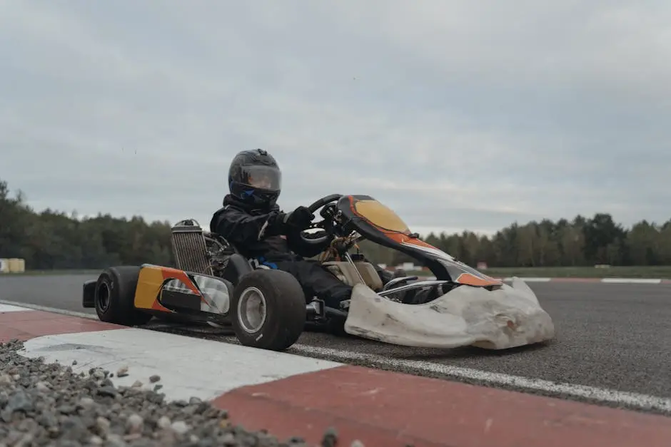 A go-kart driver in full gear navigating a racetrack during a competition.