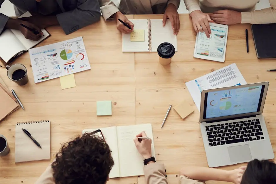 Business professionals in a collaborative team meeting, discussing charts and plans with laptops and notebooks. freelance cfo