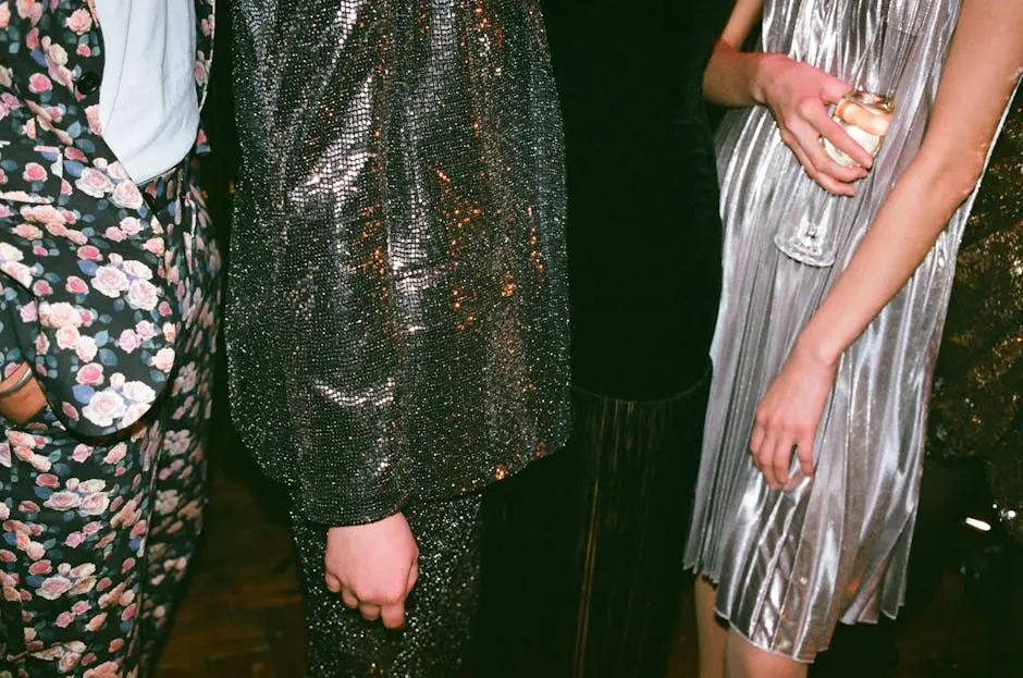 Group of adults in stylish glitter outfits and dresses at a glamorous evening event.