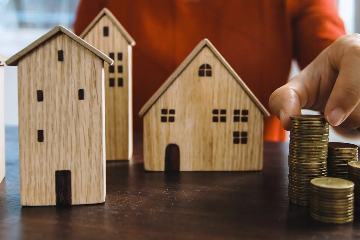 Planning investments with stacked coins and model houses on a table.