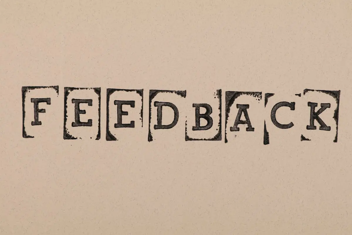Vintage-style stamped letters spelling ‘Feedback’ on textured paper background.