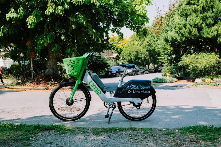 Lime bike parked on a sunny street in Seattle, offering a green transportation option among lush trees.