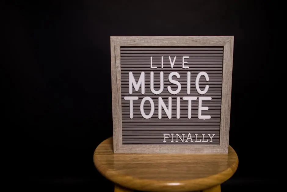 Close-up of a letter board announcing ‘Live Music Tonite Finally’ on a stool with a black background.