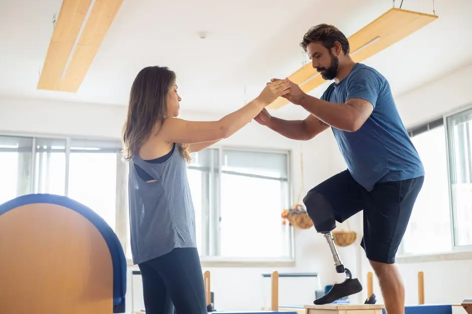 A man with a prosthetic leg exercises with a therapist in a well-lit gym environment.
