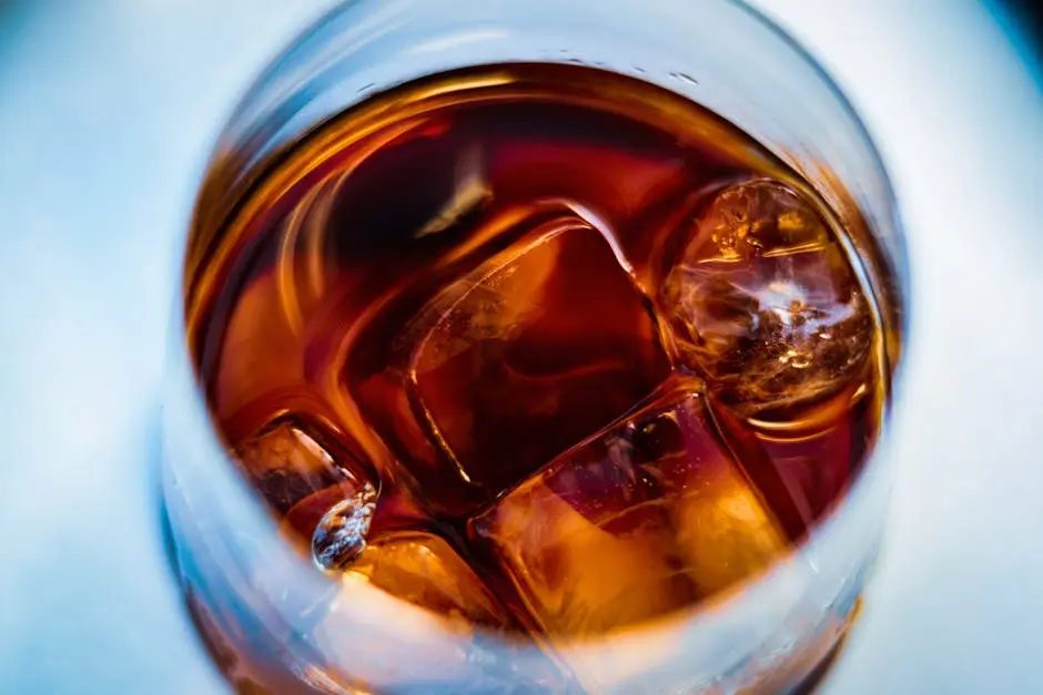 A detailed close-up of ice cubes in a glass of whiskey, capturing the rich amber hues and textures.