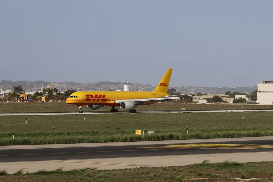 DHL cargo plane preparing for takeoff on a sunny runway, showcasing logistics and aviation.