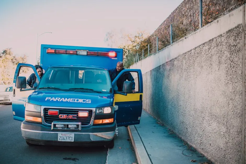 Paramedics attending to an emergency roadside with a visible GMC ambulance.