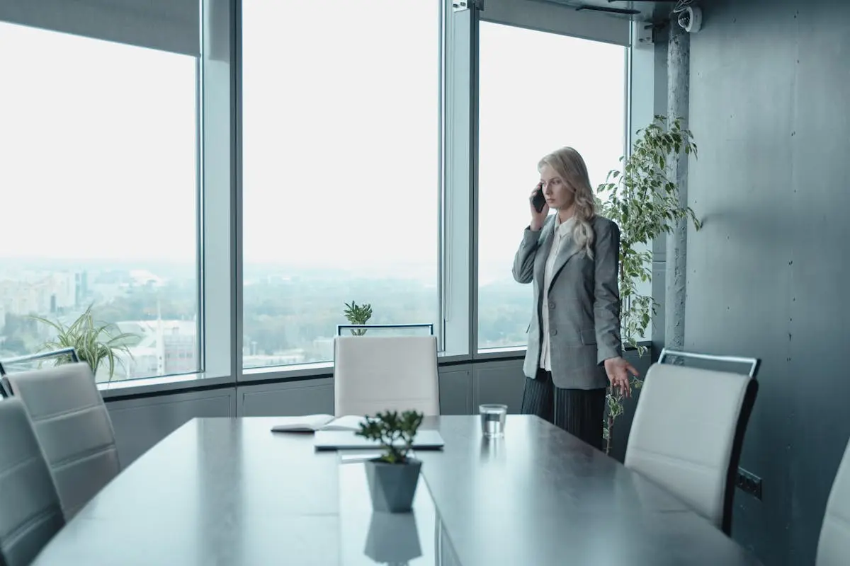 Professional businesswoman on phone in modern conference room with city view.