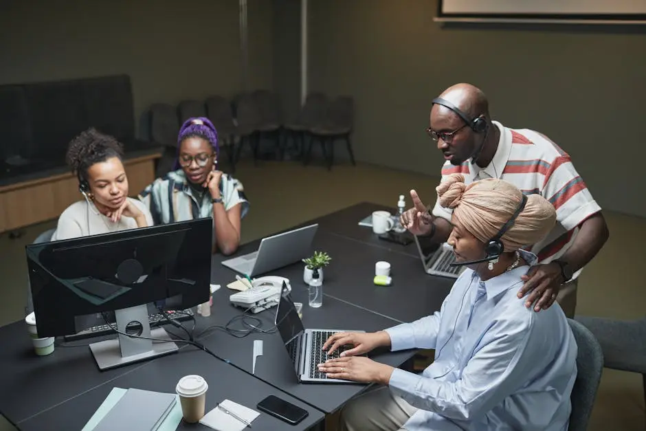 Team of coworkers in an office call center collaborating and using laptops.