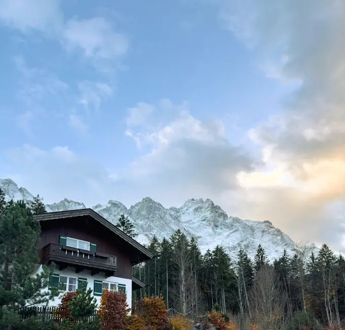 A tranquil Bavarian house nestled in a scenic forest with a stunning mountain backdrop.