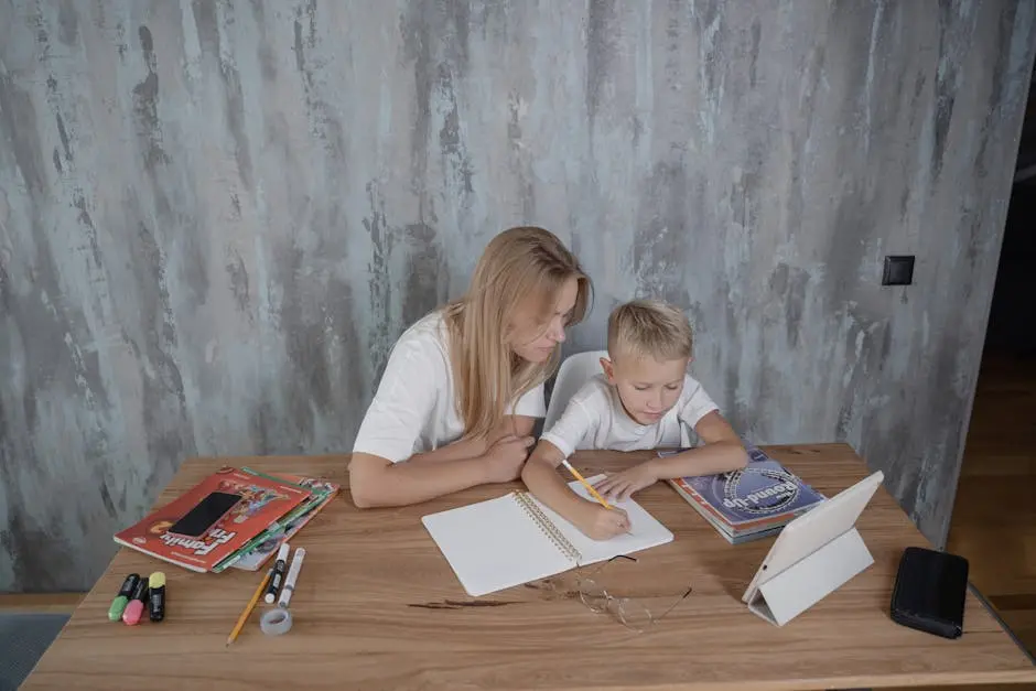 A mother guides her young son during a homework session at a desk in a cozy home setting.