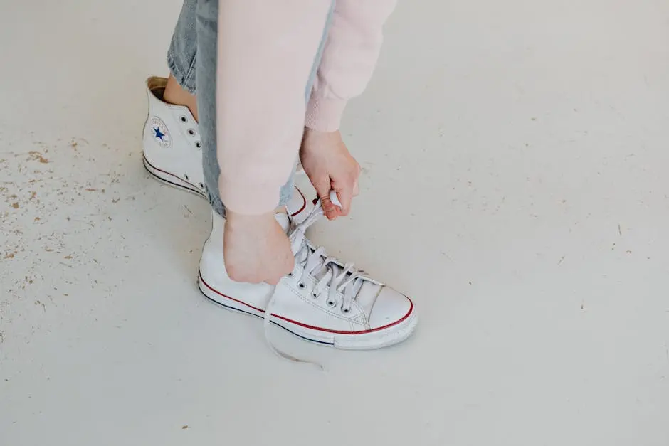 Close-up of a person tying white Converse sneakers, captured from above.